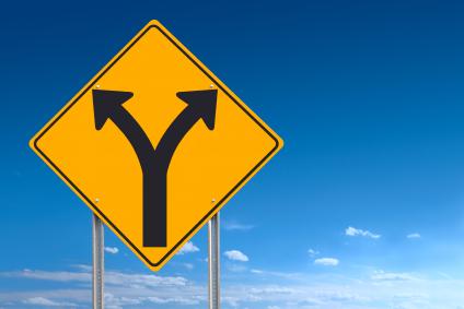 An informational traffic sign over a blue sky showing a division of directions - a clipping path is included to separate sign from bkg.