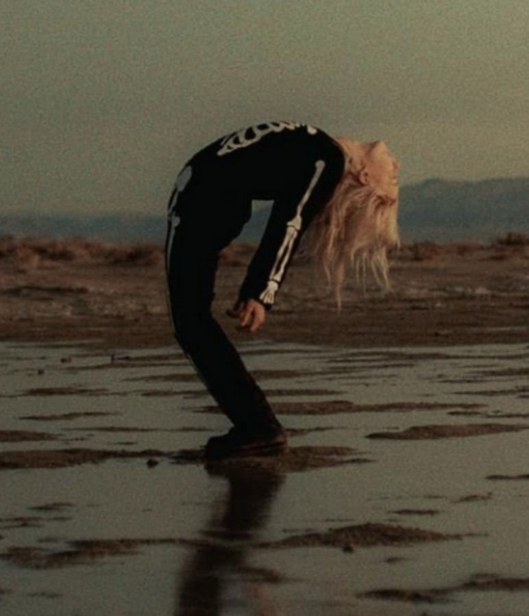 This EP cover shows Phoebe Bridgers in her skeleton-themed attire in a sandy pool of water.