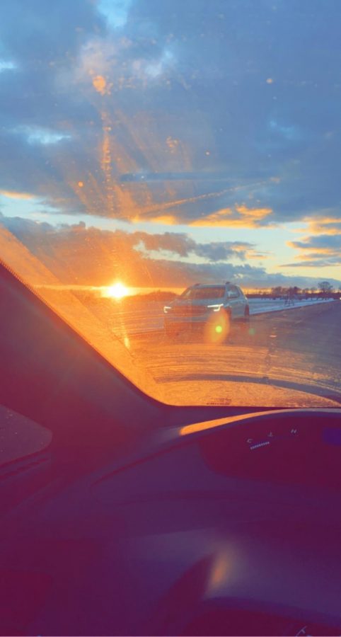 A+peaceful+drive+as+the+sun+sets+ahead+of+the+car.+