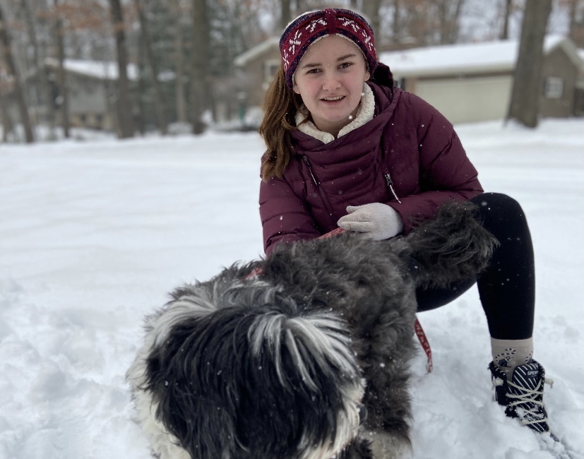 Sophomore Maya Rogne with her dog, bundled up in the snow outside