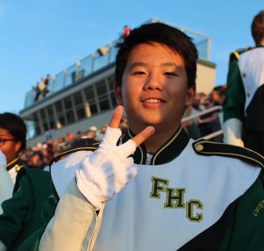 Owen Li in the stands of a football game as he participates in one of his other hobbies: playing the flute.