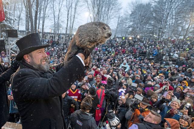 The groundhog is hoisted into the air after giving its weather prediction. 