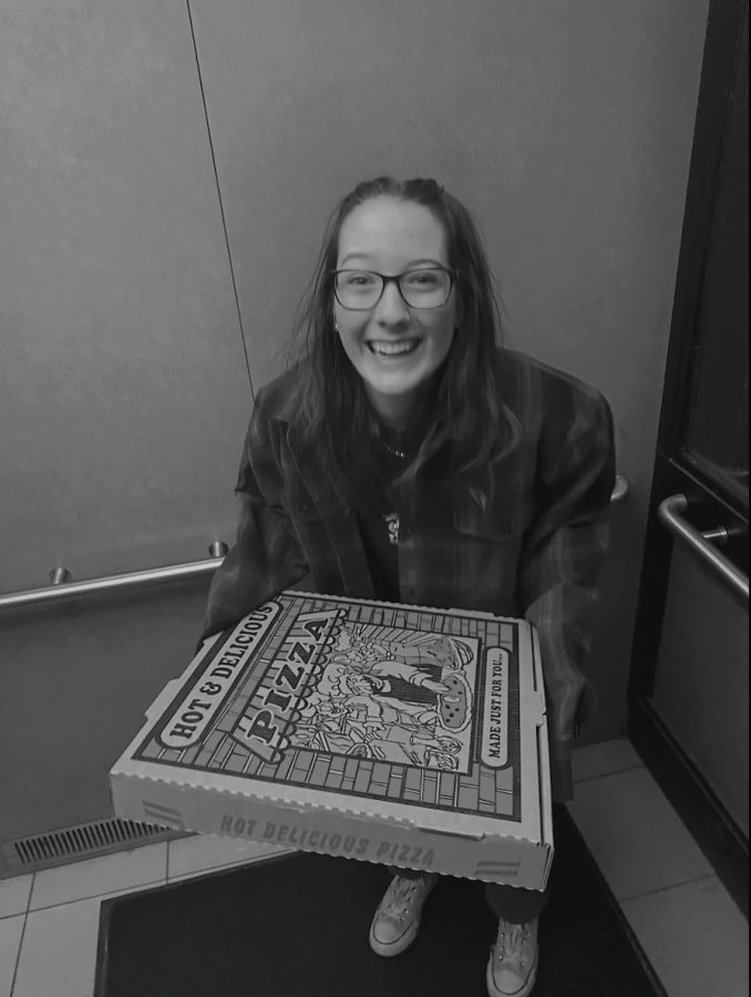 A black and white photo of me delicately wrapped in blue green holding leftover pizza.