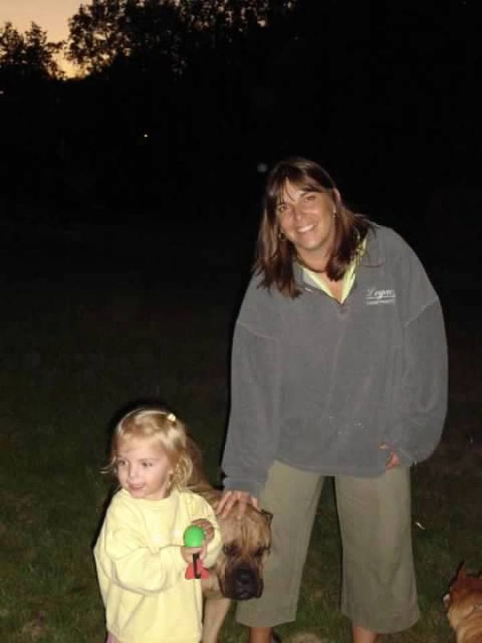 A rather blurry photo of my mom, our late-bullmastiff JJ, and me all standing around a sunset campfire. 