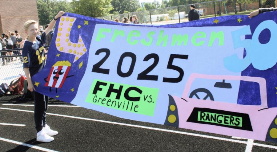 A freshman during homecoming week holding a banner. 