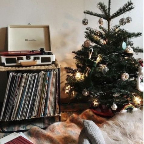A small Christmas tree sitting next to a record player, the perfect setup to listen to these songs if you have them on vinyl
