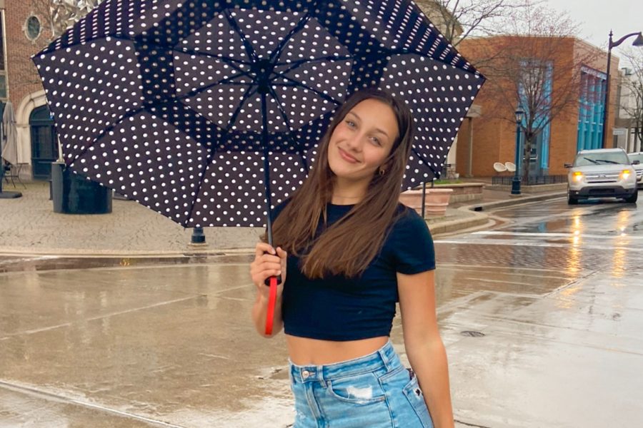 Junior Lucy Yoder stands in the rain with an umbrella.