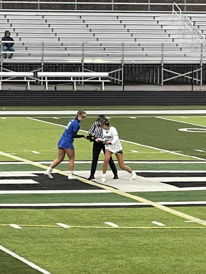 A photo of Coco Mehney taking the draw at one of her Lacrosse games. 