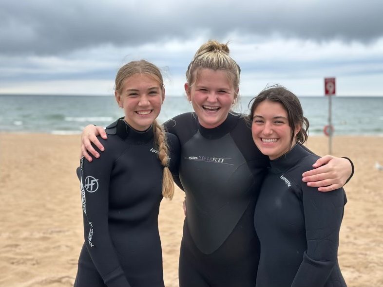 (From left to right) Seniors Maya Sneider, Madi Evans, and Eisley Sandefur while surfing in Grand Haven.