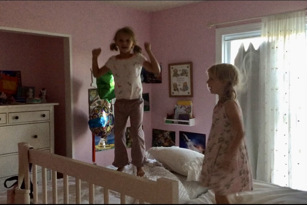 She and her sister jumping on their beds in the pink room. 