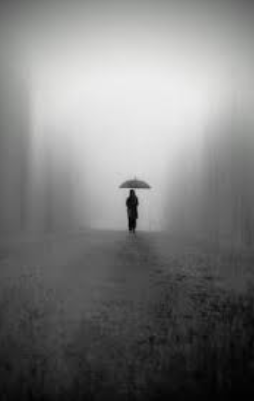 A dark figure walking alone through the pouring grey rain.