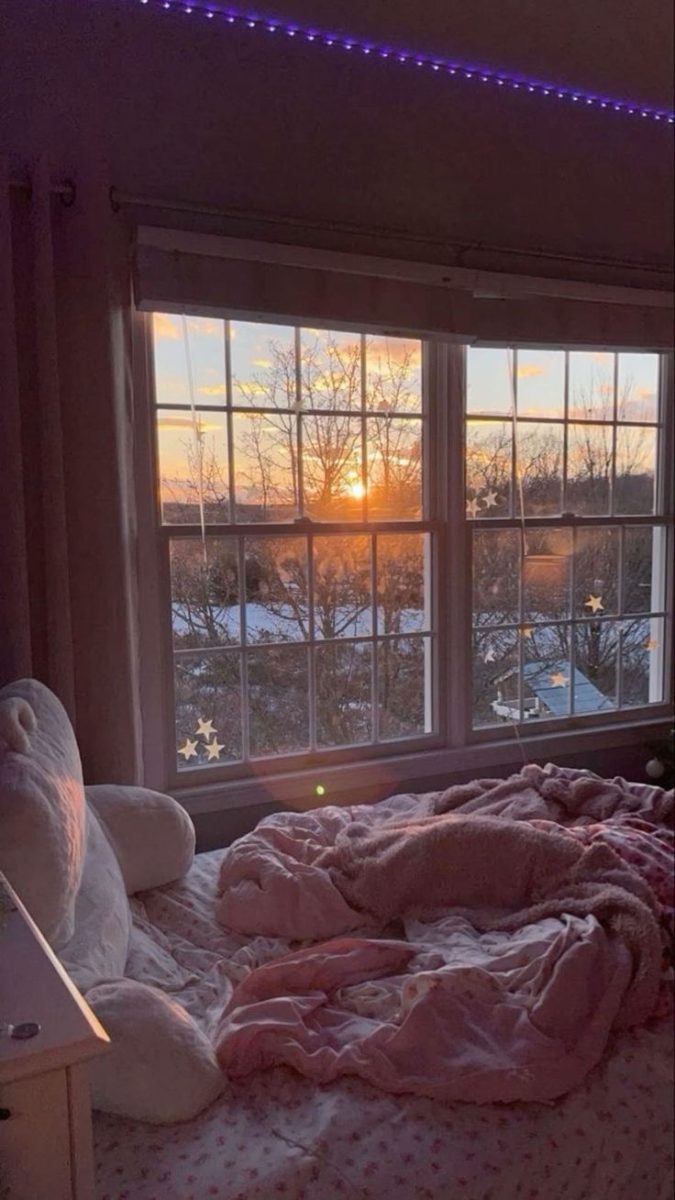 The beautiful sunset being captured by the frame of a comforting bedroom window.